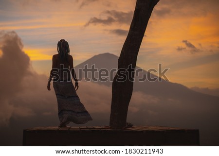Woman in a long dress stands with Bali landmark volcano Agung view. Travel blogger, Indonesia best sunset point destination. Woman retreat. High quality photo