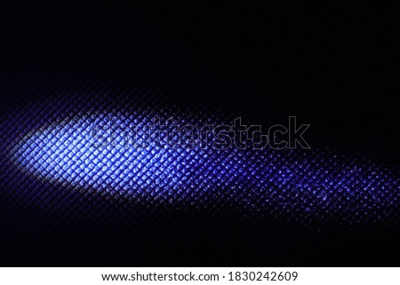 An abstract artistic image of a horizontal ellipsoid formed by a single source of light lit on blue fleece fabric texture