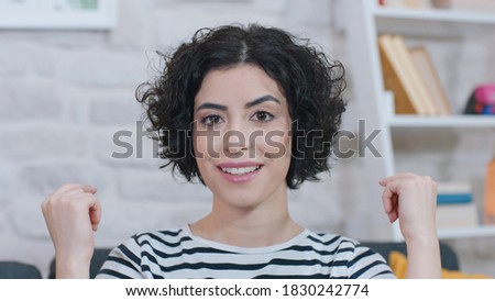 Excited young woman in pajamas playing with her curly hair.