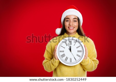 Woman in Santa hat with clock on red background, space for text. Christmas countdown