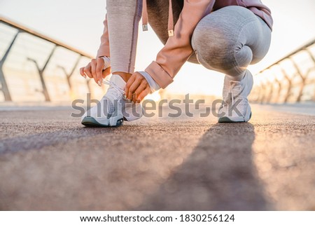 Cropped photo of a girl tying sport shoes on the bridge
