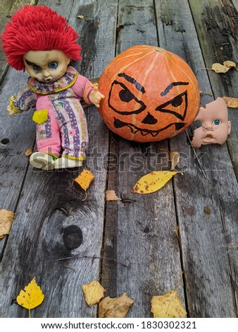 halloween pumpkin together with a gang of scary toys on an old wooden background together with autumn leaves