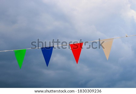 Colourful carnival bunting on show hung up against a murky blue sky 