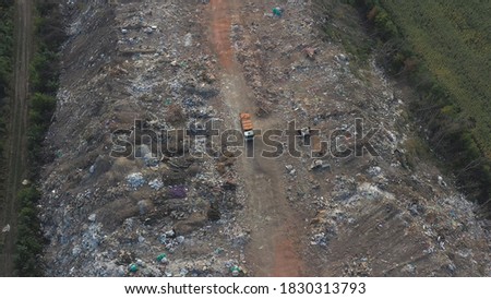 Flying over industrial truck dumping trash at open places at nature. Aerial shot of big rubbish pile lying among field in countryside. Global environmental pollution problem. Top view Slow motion.
