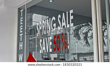 White and red text on a glass window with the inscription spring sale save 50%