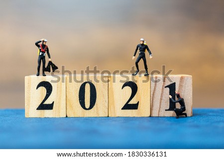 Miniature people divers diving around wooden block 2021 , Happy new Year concept