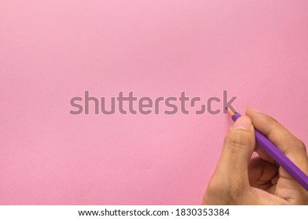 Hand holding pencil with Copy space. Idea nad Concept for Women days - Memorial day, Mothers day, Go red for women. Top view of hand with pink background. Close up