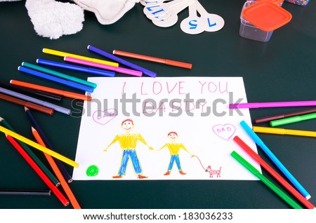 child's drawing "Daddy, I love you" and a lot of colored pencils, markers and toy on the green table