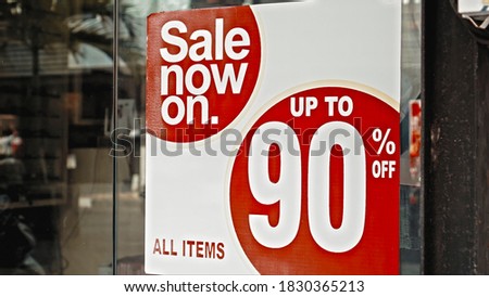 Red round sign hanging on a glass window with the inscription sale now on up to 90% off