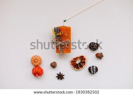Autumn still life: candles, cinnamon, chestnuts, acorns, dry orange slices on white background. Hygge lifestyle, cozy home decor. Thanksgiving, Halloween background. Flat lay, top view, minimal style