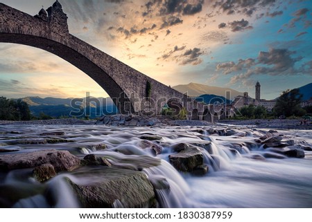 View of the old medieval bridge, called "Ponte del Diavolo" or "Ponte Gobbo" over the river Trebbia in the small village of Bobbio (northern Italy)