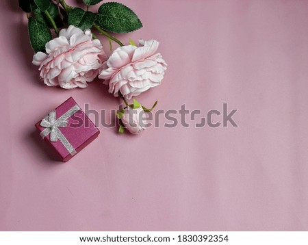 Fake silk pink peonies, pink gift box on textured pink background. Copy space. Top view angle. Selective focus
