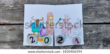 Year of the bull 2021. Zodiac signs Taurus with a frying pan by the stove and a ram with a suitcase, traveler. Against the background of a wooden surface. 