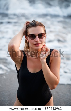 Young beautiful woman enjoying the breeze on the beach. Portrait of a carefree girl relaxing at the sea. Beautiful smiling woman enjoying the sun on the beach.