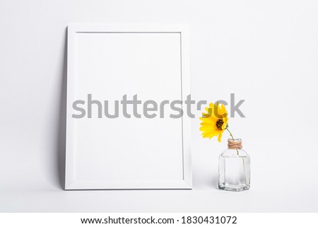 White empty picture frame mock up with yellow flower in glass jar