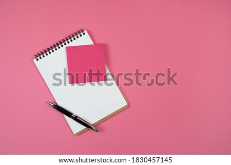 Notepad and pen on a pink background.