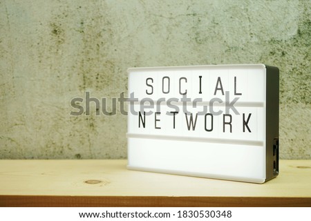 Social Network word in light box on wooden background