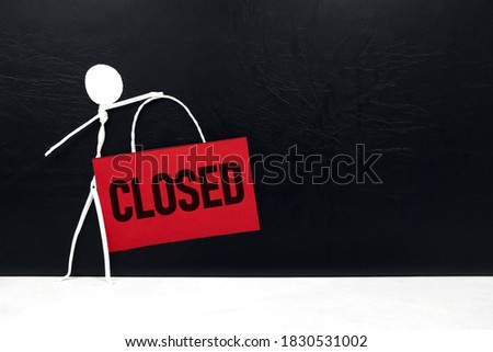 Business closure and bankruptcy concept. Stick man figure holding red Closed signage in black background with copy space.