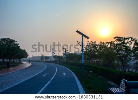 Jogging and cycling tracks in Al Warqa park, Dubai, UAE early in the morning. Lamp post powered by solar panels can be seen in the picture as well as minaret of a mosque. Outdoors