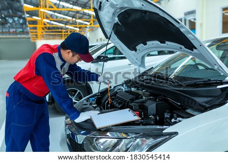 Auto mechanic checking car engine oil in car auto repair service center. Royalty-Free Stock Photo #1830545414