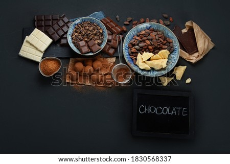 Delicious chocolate bars and pieces. Top view, copy space, chalkboard
