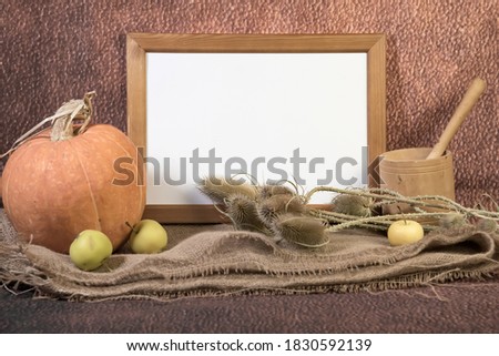 Portrait empty wooden frame mockup with pumpkin, mortar, pestle and dry grass on sackcloth. Brown background. Thanksgiving, Halloween concept. 