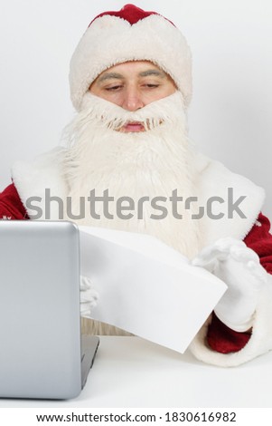 Christmas and New Year concept. Santa Claus is sitting at his desk and reading letters.