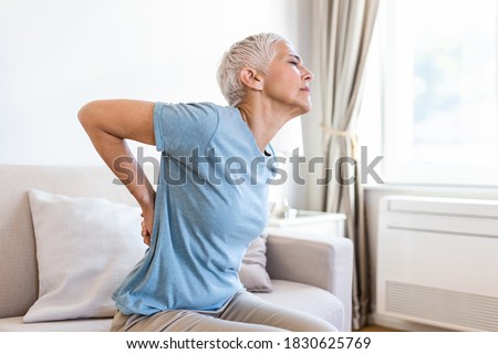 Matur Woman suffering from lower back pain. Mature woman resting with back pain. Female lower back pain. Senior woman injury suffering from backache