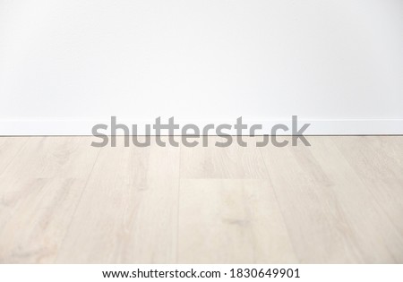 light oak laminate with white baseboard and white wall as background for design concepts Royalty-Free Stock Photo #1830649901