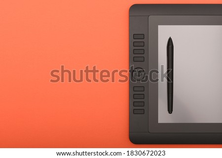 Graphic monitor stylus on orange color table. Black tablet computer with blank screen. High resolution photo. Full depth of field. Working environment concept