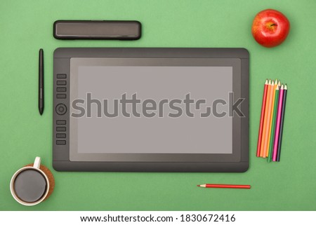 Graphic monitor stylus and glove on green color table. Black tablet computer with blank screen. High resolution photo. Full depth of field. Working environment concept