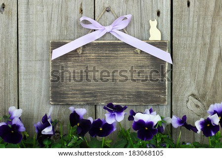 Blank rustic sign with purple flowers (pansies) against wooden background
