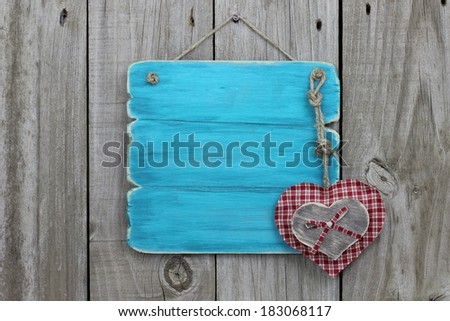 Blank antique blue (teal) sign with plaid and wood heart hanging on wooden background