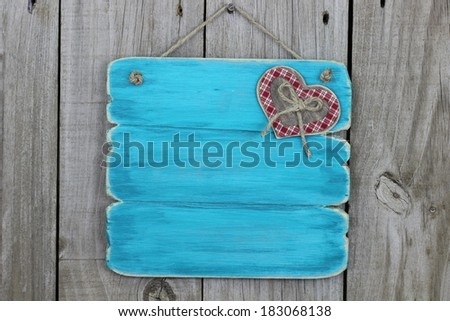 Blank antique blue sign with plaid heart hanging on wood background