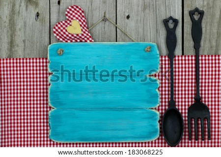 Blank antique blue (teal) sign with gingham tablecloth and cast iron spoon and fork
