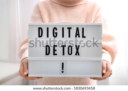 Woman holding lightbox with phrase DIGITAL DETOX at home, closeup