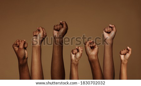 Cropped shot of hands raised with closed fists. Multiple hands raised up with closed fist symbolizing the black lives matter movement. Royalty-Free Stock Photo #1830702032