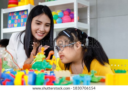 Asian girl with Down's syndrome play toy with her teacher in classroom. Concept disabled kid learning. Royalty-Free Stock Photo #1830706154