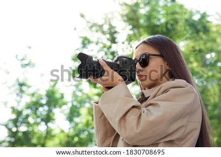 Private detective with camera spying in park