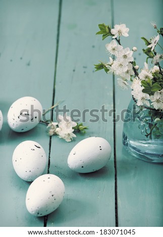 Easter eggs and vase of blooming branches on vibrant wooden table