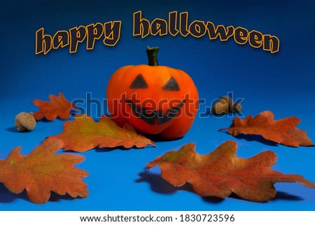 Halloween holiday background with pumpkin-looking orange pepper and autumn leaves on a dark blue background. Happy Halloween, trick or treat.