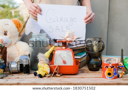 Woman hold garage sale sign. Selling old stuff in the yard. 
