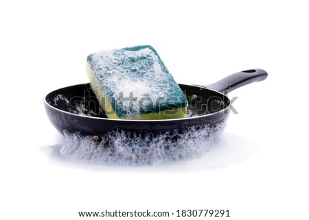 The pan is cleaned with green scouring pads with foam bubbles from dishwashing detergent - isolated on a white background.