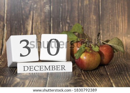 December 30. Day 30 of month. Calendar cube on wooden background with red apples, concept of business and an important event. Winter season.
