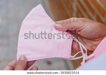 pink mask from COVID19 and breast cancer hold by woman hands