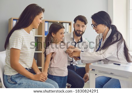 Woman doctor listens baby girl heart with stethoscope. Family mother, father and daughter at consultation with doctor