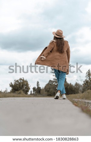 girl in a beige hat with her back in nature