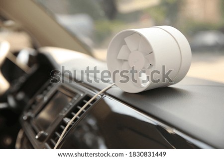 Portable fan on dashboard in car. Summer heat