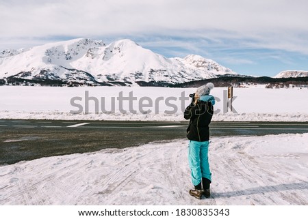 Photographer woman photographs a snowy mountain in winter.