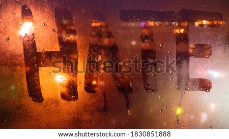 Hate, negative emotions. Inscription on the fogged glass, night city on the background. image with tinting and noise effect